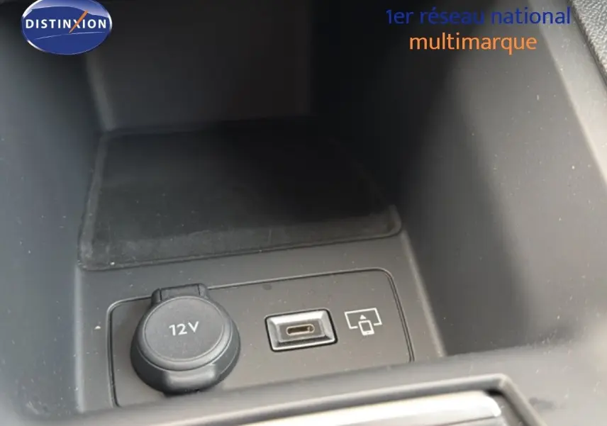 Gros plan sur la prise 12V et port USB dans le compartiment central d'une Peugeot 308 noire hybride 2025.