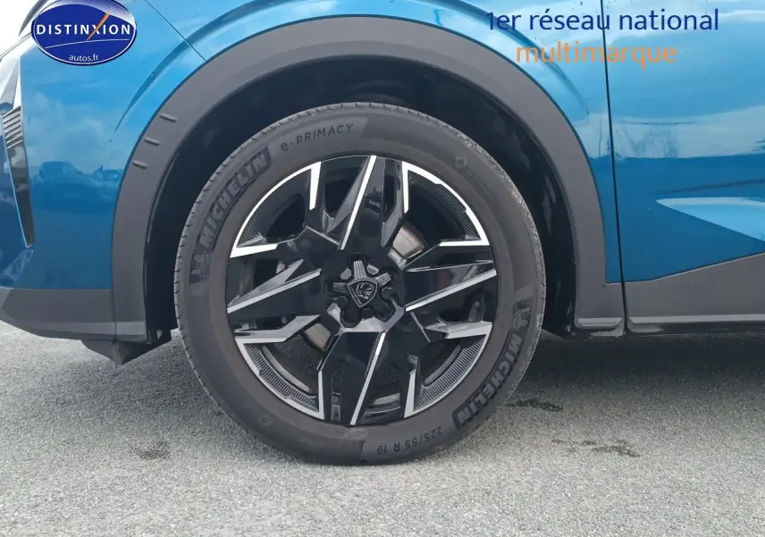 Gros plan sur la roue avant gauche avec jante alu noire et argentée du Peugeot 3008 bleu 2025.