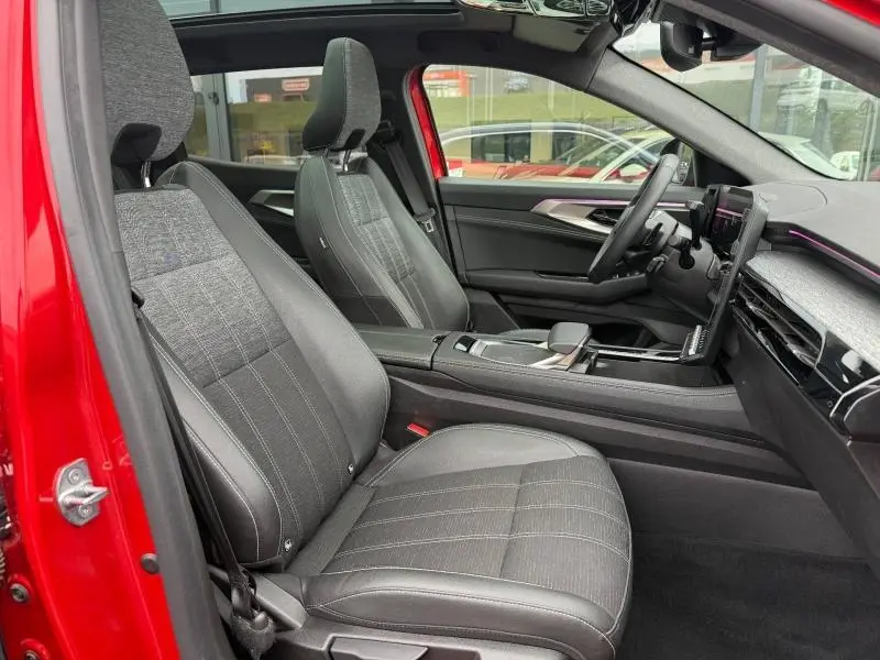 Vue intérieure côté conducteur du Renault Austral 2025 rouge Flamme, sièges tissu et tableau de bord moderne avec écran tactile.