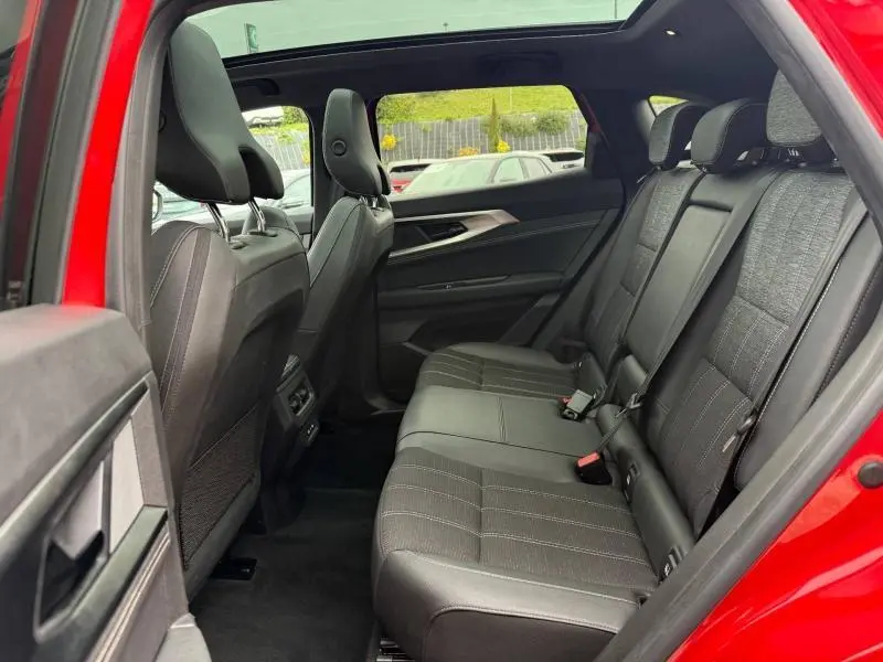 Vue intérieure arrière côté gauche du Renault Austral 2025 rouge flamme, montrant les sièges arrière en tissu gris avec surpiqûres.