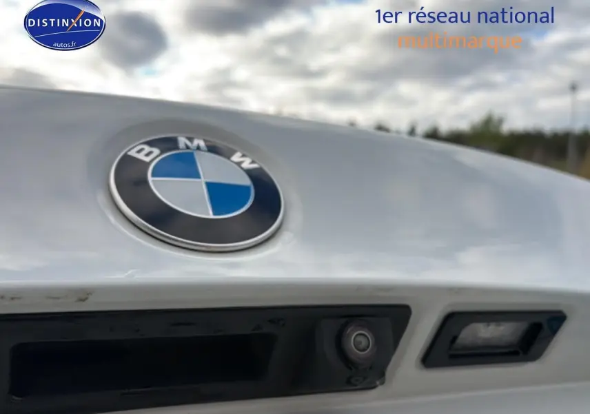Gros plan sur le logo BMW gris argent avec caméra de recul et poignée de coffre sur une Série 2 Active Tourer.