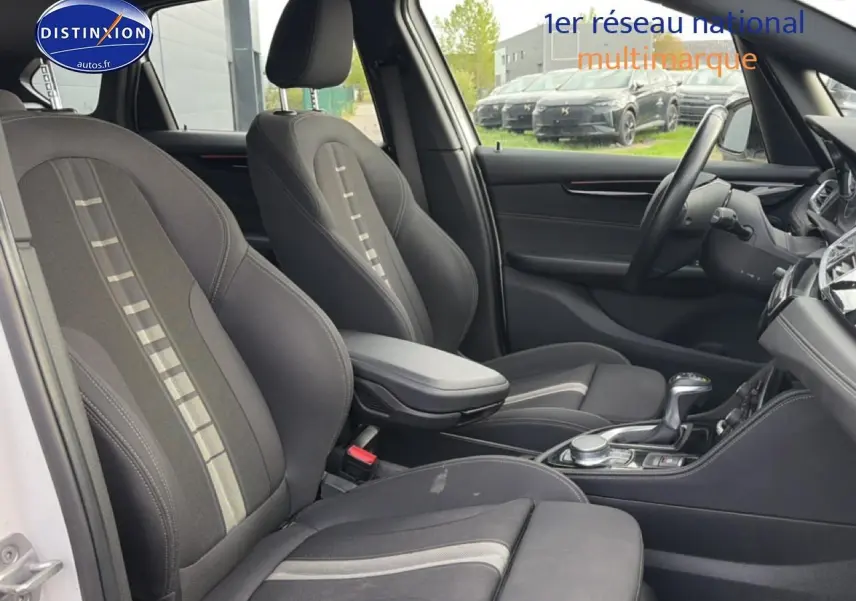 Vue intérieure côté conducteur de la BMW Série 2 Active Tourer 225xea, sièges tissu anthracite avec accoudoir central.