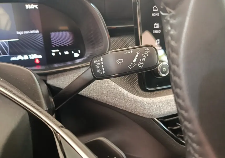 Gros plan sur la commande d’essuie-glace à gauche du volant cuir alu du Skoda Scala 1.5 TSI 2024, tableau de bord numérique visible.