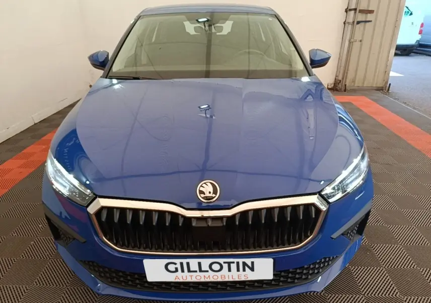 Vue avant d'une Skoda Scala 1.5 TSI bleu, avec calandre noire et phares LED allumés dans un garage.