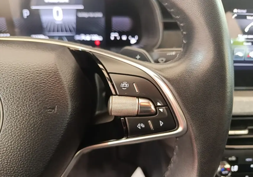 Gros plan sur le volant cuir et alu de la Skoda Scala 2024 avec commandes multifonctions et tableau de bord numérique flou.