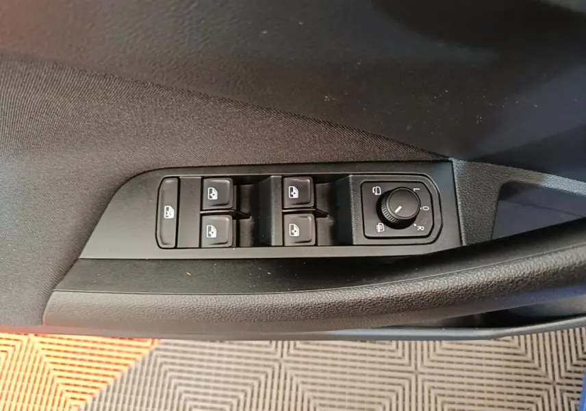 Gros plan sur les commandes des vitres et rétroviseurs côté conducteur d'une Skoda Scala 2024 bleu.