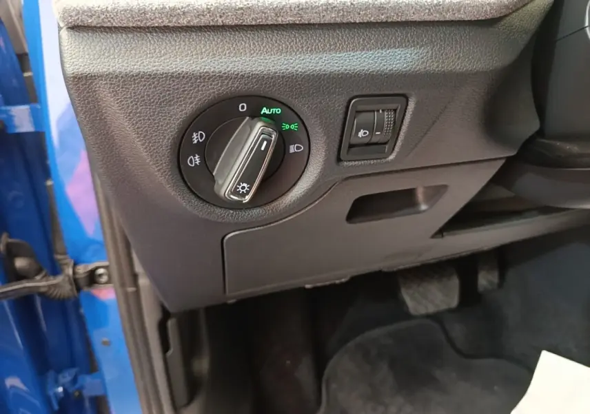 Détail du tableau de bord côté gauche d’une Skoda Scala bleu 2024 avec commande des phares et réglage hauteur.