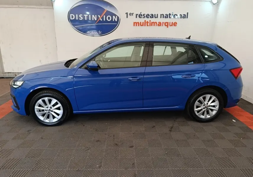 Vue latérale droite d'une Skoda Scala bleu 2024 stationnée en intérieur avec jantes alliage argentées.
