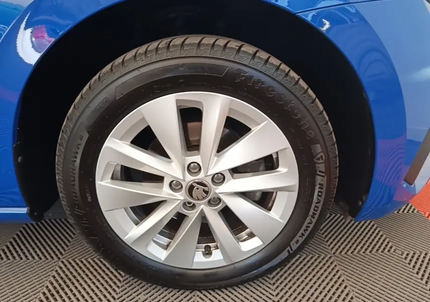 Gros plan sur la roue avant gauche d’une Skoda Scala bleu, avec jante alliage argentée et pneu Firestone.