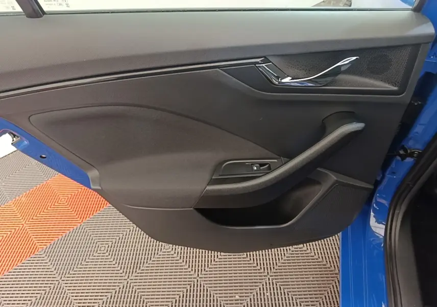 Gros plan sur la porte avant gauche bleue d'une Skoda Scala 2024, avec poignée chromée et commande de vitre intégrée.