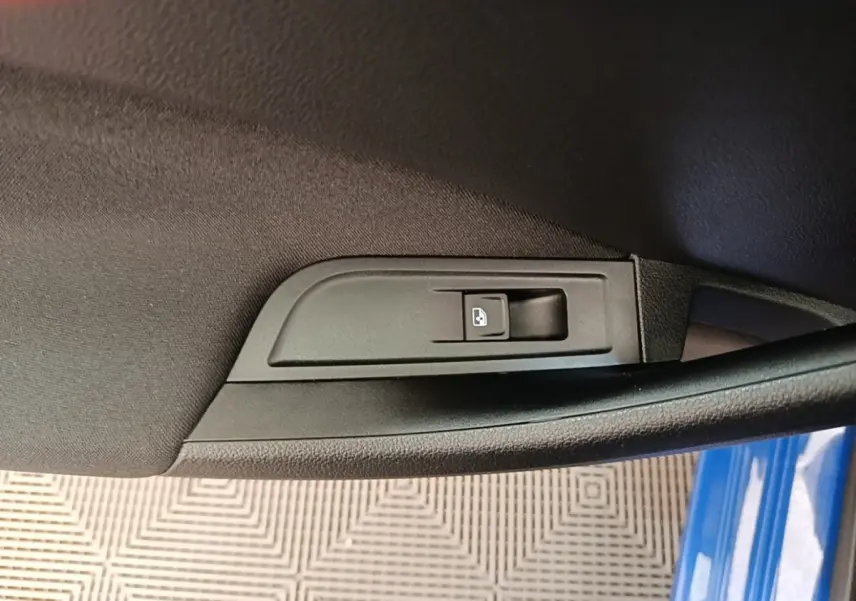 Détail de la commande de verrouillage centralisé sur la porte côté gauche d’une Skoda Scala bleue 2024.