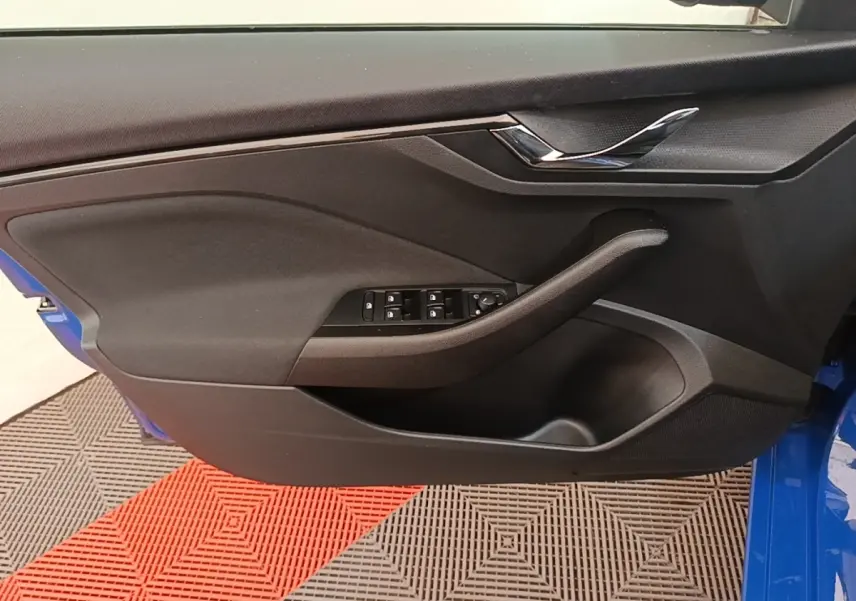 Vue rapprochée de la porte avant gauche d'une Skoda Scala bleue, avec commandes de vitres et poignée noire.
