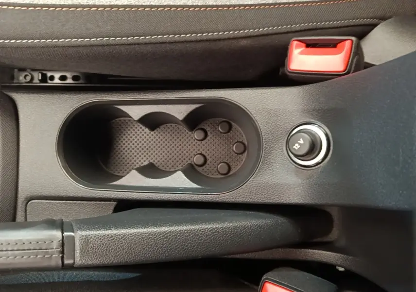 Vue rapprochée de la console centrale de la Skoda Scala 2024, montrant porte-gobelets, frein à main et prise 12V.