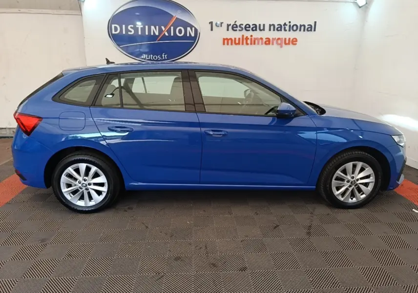 Profil droit d'une Skoda Scala bleu 2024, avec jantes alliage et vitres teintées, en intérieur showroom.
