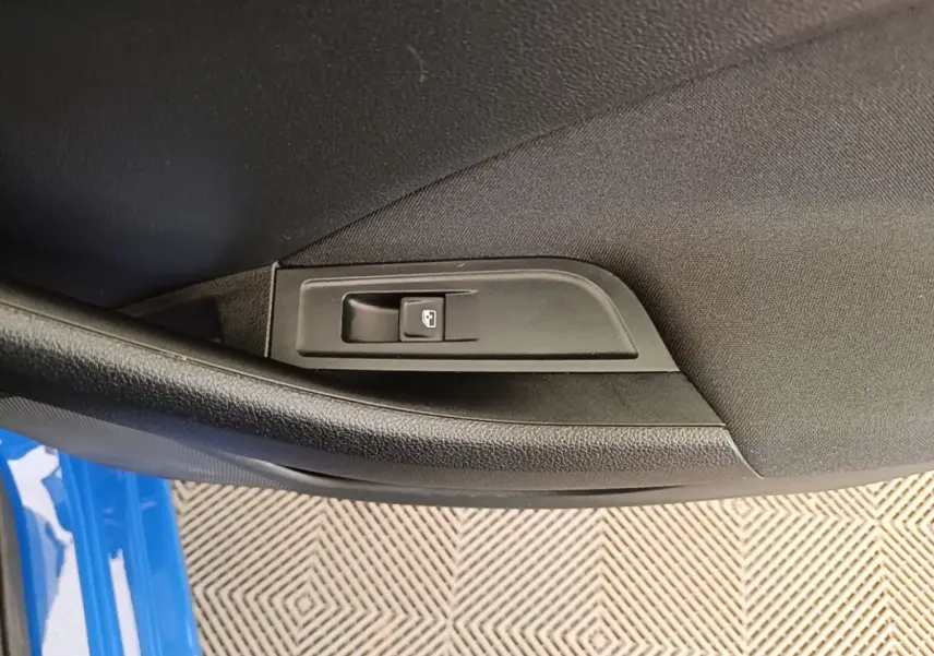 Gros plan sur le bouton de commande de lève-vitre intégré dans la porte côté gauche d’une Skoda Scala bleu.