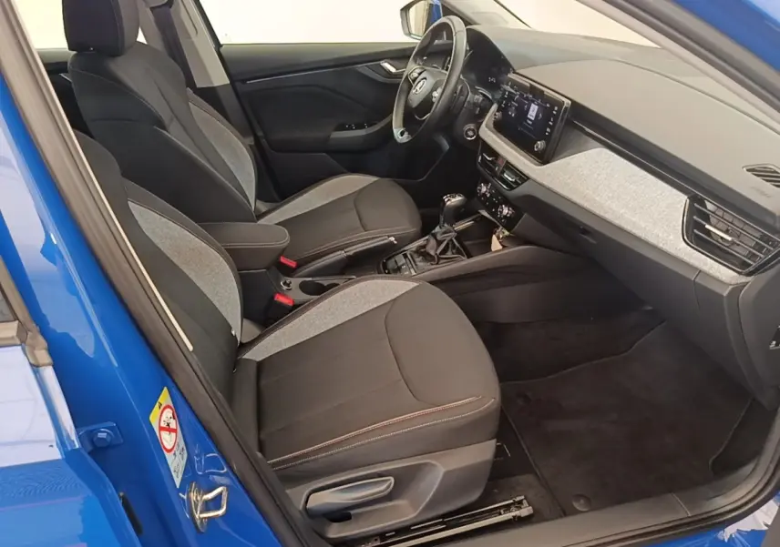 Vue intérieure côté conducteur de la Skoda Scala 1.5 TSI bleu, avec sièges bi-matière et tableau de bord moderne.