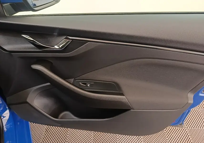 Vue intérieure de la porte avant gauche d’une Skoda Scala 2024 bleu, avec poignée chromée et accoudoir noir.
