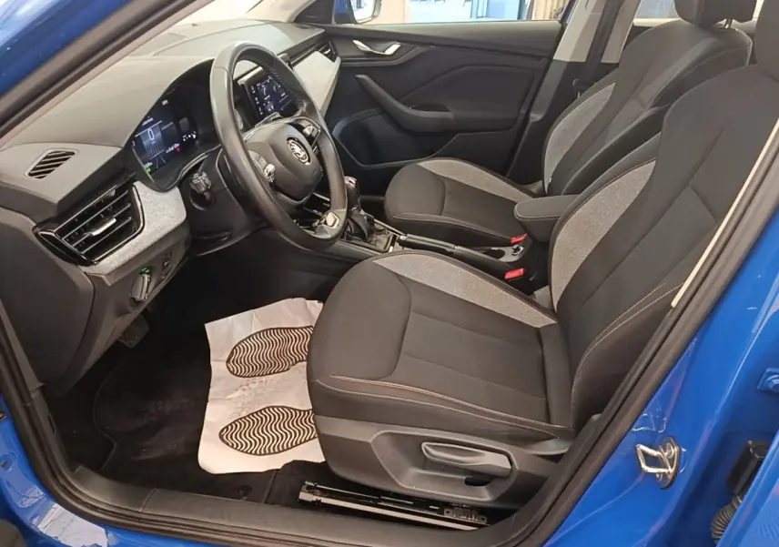 Vue intérieure côté conducteur d'une Skoda Scala 2024 bleu, sièges tissu noir et gris avec volant multifonctions cuir et alu.