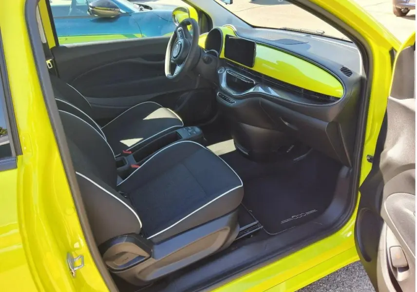 Intérieur de la FIAT 500 électrique jaune Acid, vue côté conducteur avec tableau de bord et sièges noirs.