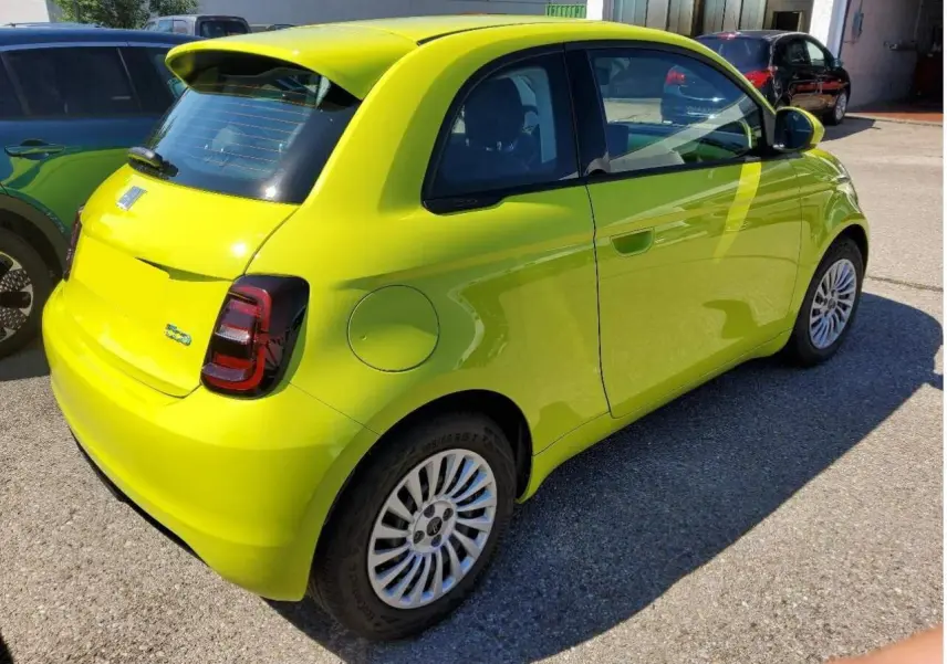 Vue 3/4 arrière droite d'une FIAT 500 électrique jaune Acid avec feux arrière foncés et jantes multibranches.