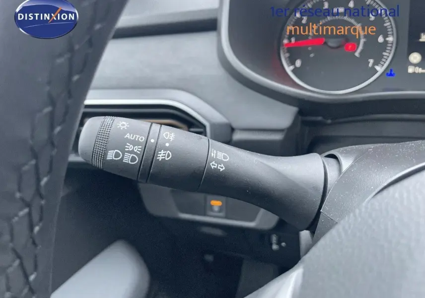 Gros plan sur la commande des phares et clignotants du tableau de bord d'une Dacia Sandero Stepway gris schiste 2024.