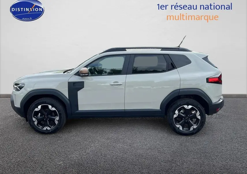 Profil côté gauche du Dacia Duster 2025 couleur Sandstone avec jantes alu et barres de toit noires.