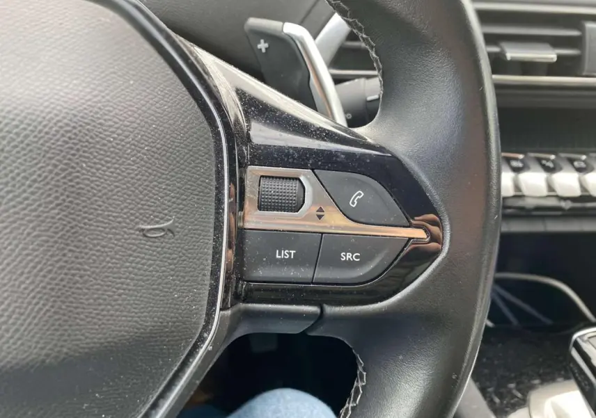 Gros plan sur la partie gauche du volant noir du Peugeot 3008 2019 avec commandes audio et téléphone intégrées.