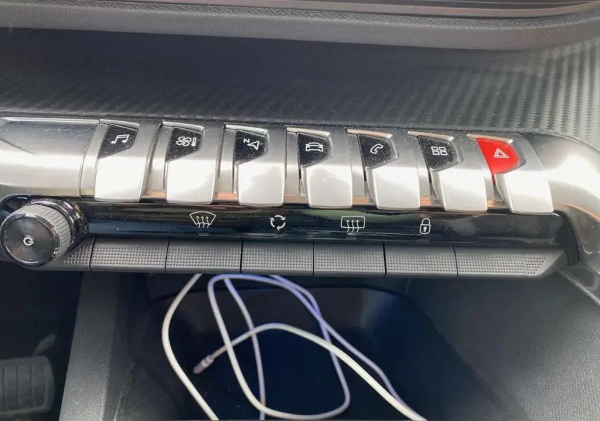 Gros plan sur la rangée de boutons chromés du tableau de bord du Peugeot 3008 noir, version Active 2019.