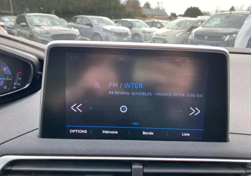 Écran tactile central du tableau de bord du Peugeot 3008 noir, avec affichage radio FM France Inter, vue intérieure avant.