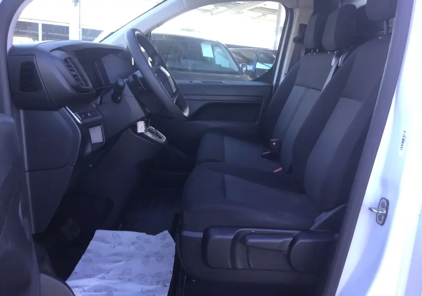 Intérieur du FIAT Scudo Fourgon blanc 2024, vue côté conducteur montrant les sièges noirs et le tableau de bord moderne.