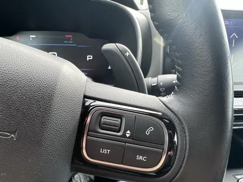 Gros plan sur les commandes au volant d'une Citroën C5 Aircross 2021, version Blue Tijuca, avec palette de changement de vitesse.