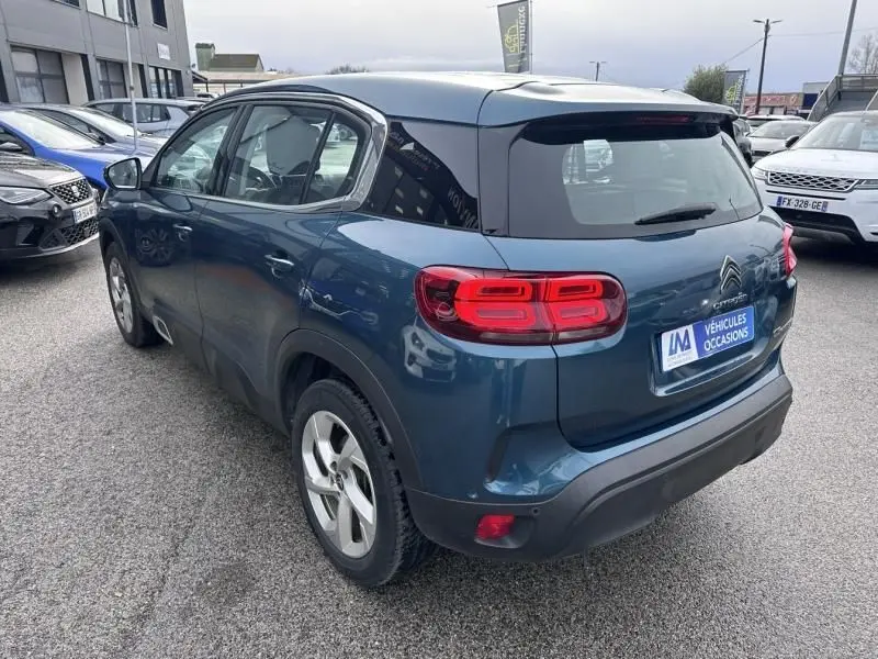 Vue 3/4 arrière droite d'un Citroën C5 Aircross Bleu Tijuca avec feux arrière LED distinctifs, sur parking extérieur.