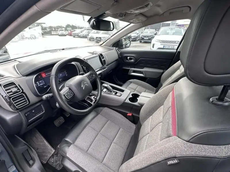 Vue intérieure côté conducteur du Citroën C5 Aircross 2021, sièges gris avec surpiqûres rouges et tableau de bord moderne.