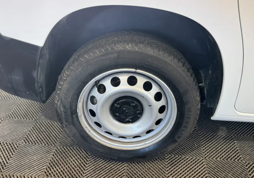 Gros plan sur la roue arrière droite en jante acier du Citroën Berlingo blanc, avec partie basse de la carrosserie visible.