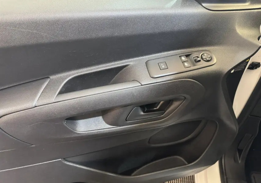 Vue intérieure côté conducteur de la porte noire du Citroën Berlingo blanc, avec commandes électriques des vitres et rétroviseurs.