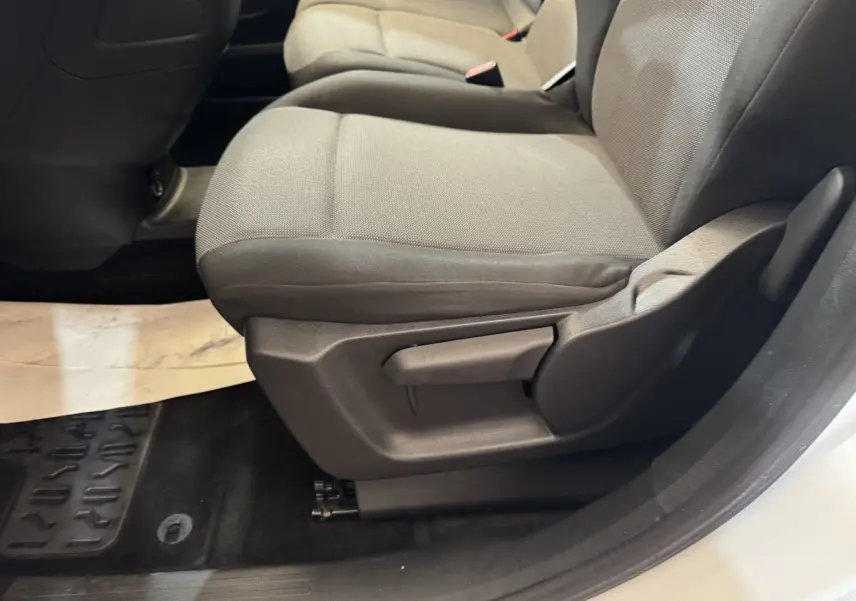 Gros plan sur le siège avant droit gris du Citroën Berlingo blanc, montrant le réglage manuel de l'assise.