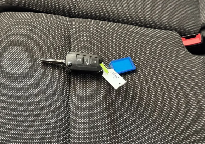 Clé de voiture noire posée sur un siège tissu gris foncé à motifs blancs, intérieur d'un Citroën Berlingo 2020.