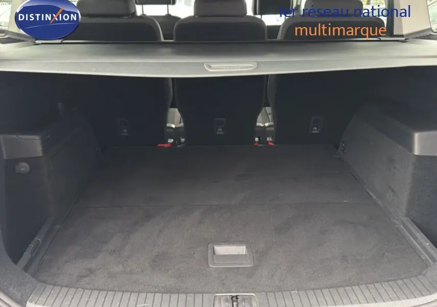 Coffre spacieux du Volkswagen Touran blanc 2018 vu de l'arrière avec banquette arrière rabattue et cache-bagages.