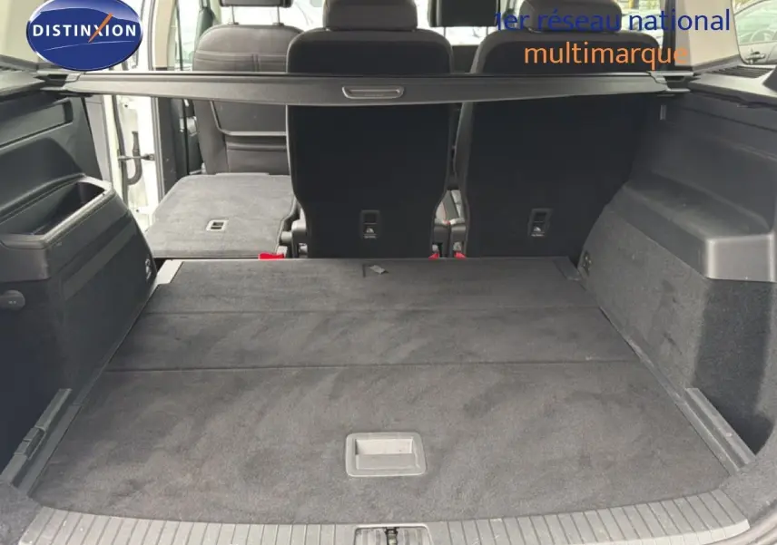 Vue arrière du coffre spacieux du Volkswagen Touran blanc 2018 avec banquette arrière partiellement rabattue.