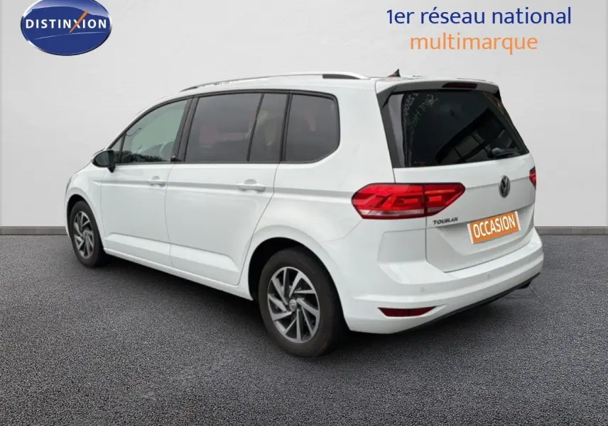 Vue 3/4 arrière droite d'un Volkswagen Touran blanc de 2018 avec feux arrière LED et jantes alliage bicolores.