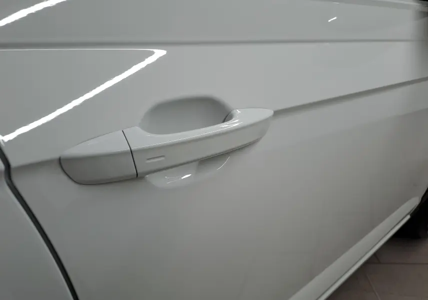 Gros plan sur la poignée de porte côté gauche du Volkswagen Taigo blanc pur avec toit noir, finition R-Line Edition 2025.