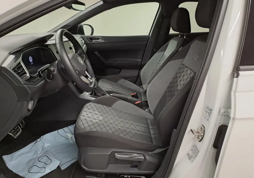 Vue intérieure côté conducteur du Volkswagen Taigo 1.5 TSI 150 DSG7 R-Line Edition avec sièges tissu gris à motifs et volant multifonction.