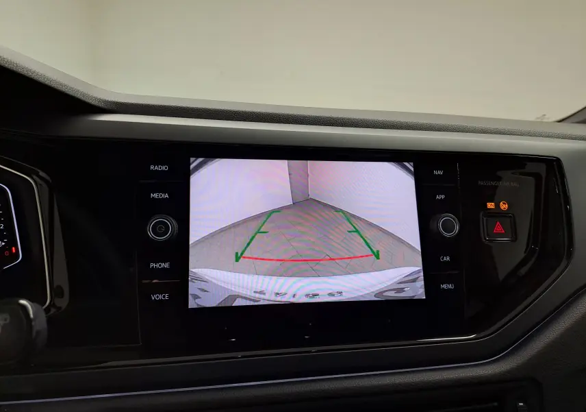 Écran central affichant la caméra de recul du Volkswagen Taigo blanc pur avec toit noir, vue arrière en stationnement.