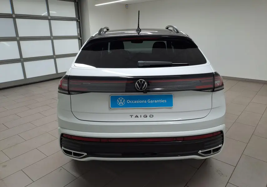 Vue arrière d'un Volkswagen Taigo blanc pur avec toit noir, feux arrière connectés et double sortie d'échappement chromée.