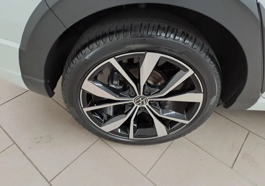 Gros plan sur la jante alliage 18 pouces "Misano" bicolore noir et argent du Volkswagen Taigo blanc toit noir.