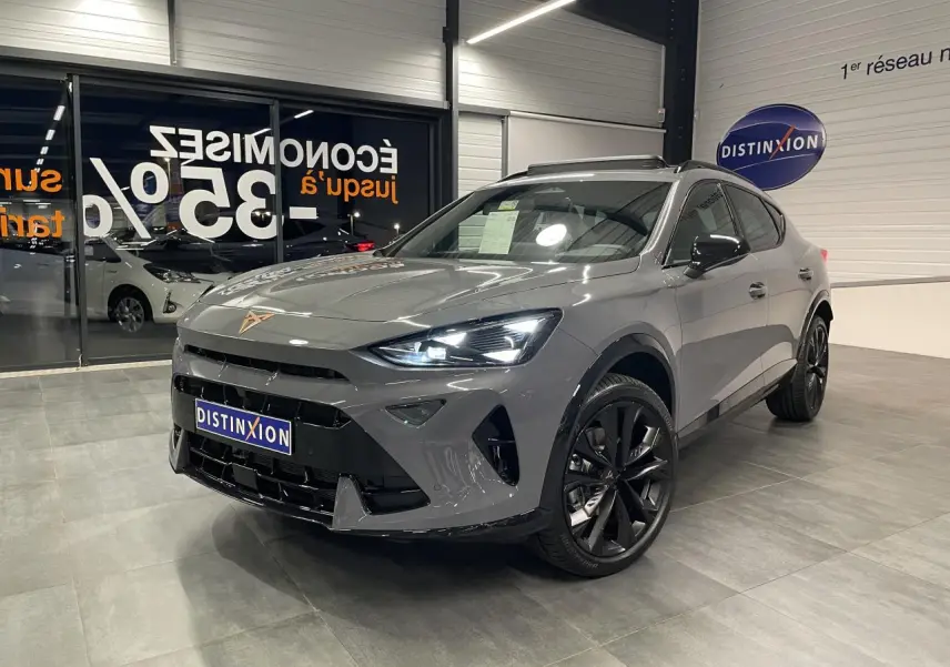 Vue 3/4 avant droit du CUPRA Formentor gris Graphene avec jantes noires et signature lumineuse Tri-LED allumée en intérieur showroom.