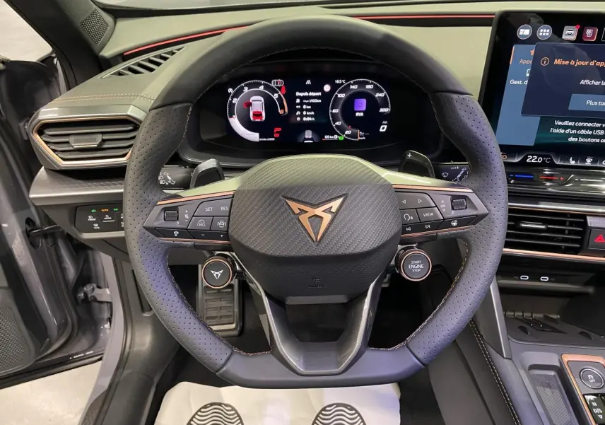 Vue intérieure centrée sur le volant perforé noir avec logo Cupra cuivré et tableau de bord digital du Formentor gris Graphene.