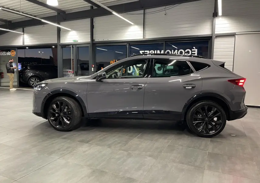 Vue de profil côté gauche d’un CUPRA Formentor gris Graphene avec jantes alliage noires en showroom.