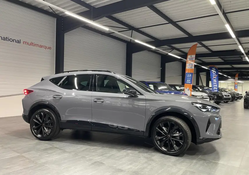 Vue de profil droit du CUPRA Formentor gris Graphene avec jantes alliage noires en showroom lumineux.