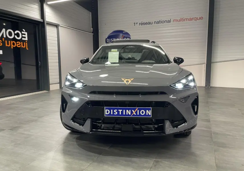 Vue frontale d'un CUPRA Formentor gris Graphene avec phares allumés et logo CUPRA cuivré visible sur le capot.